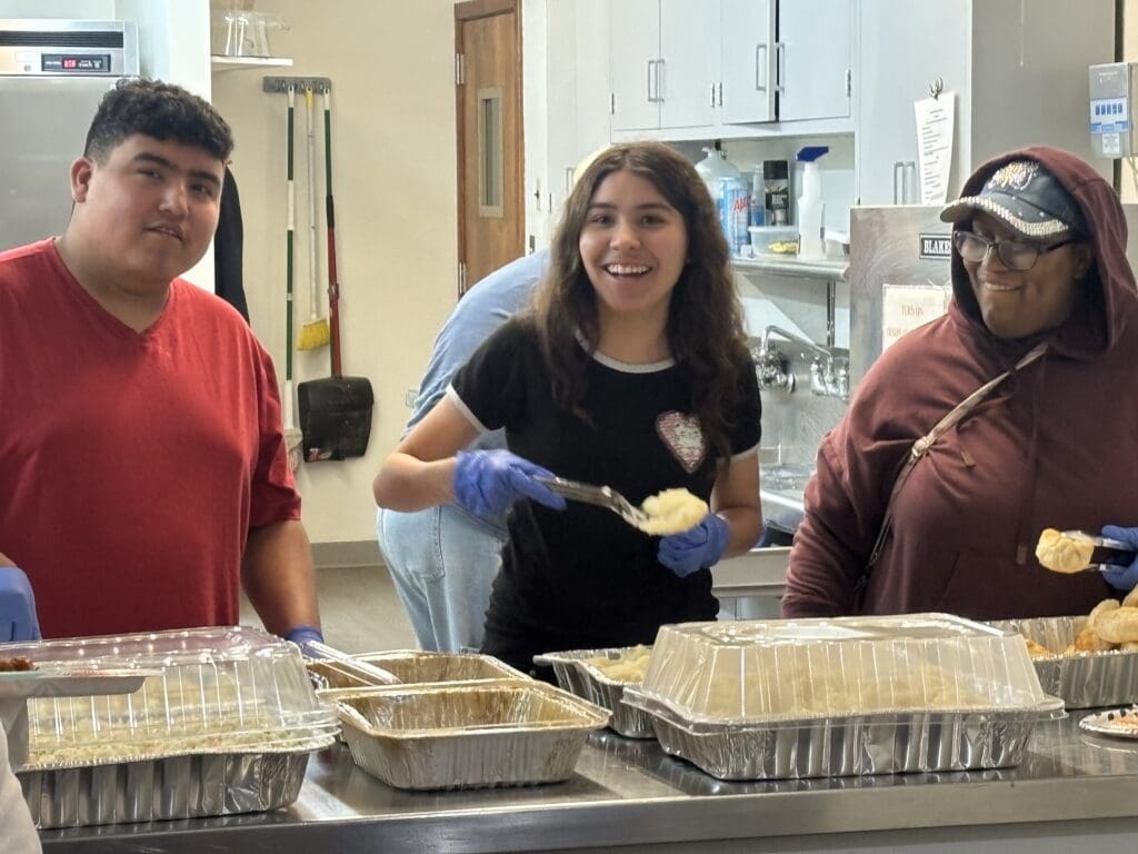 A client helps with serving food for a group activity involving respite