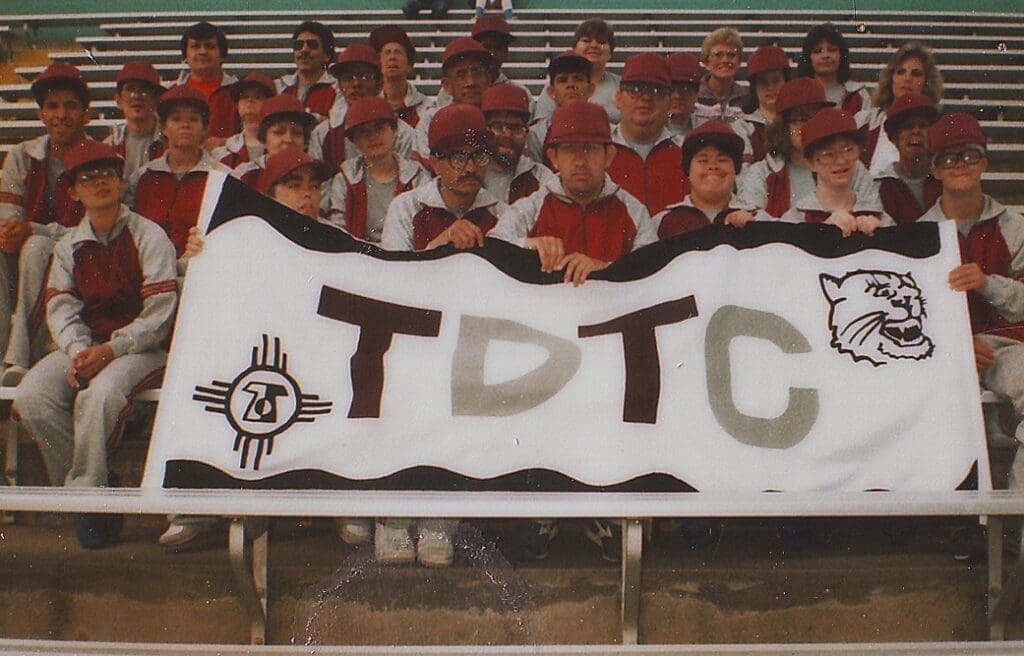 A group picture of about 20 clients holding the 80's version of Tobosa's logo